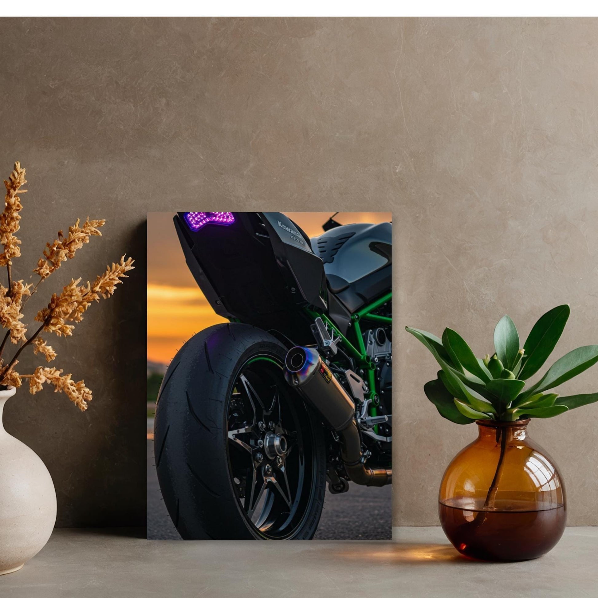 a close-up view of a motorcycle, with a focus on the rear wheel and exhaust pipe. The motorcycle is parked on a road, with a sunset in the background. The motorcycle is positioned in the center of the frame, and the surrounding objects include a vase with flowers and a potted plant.