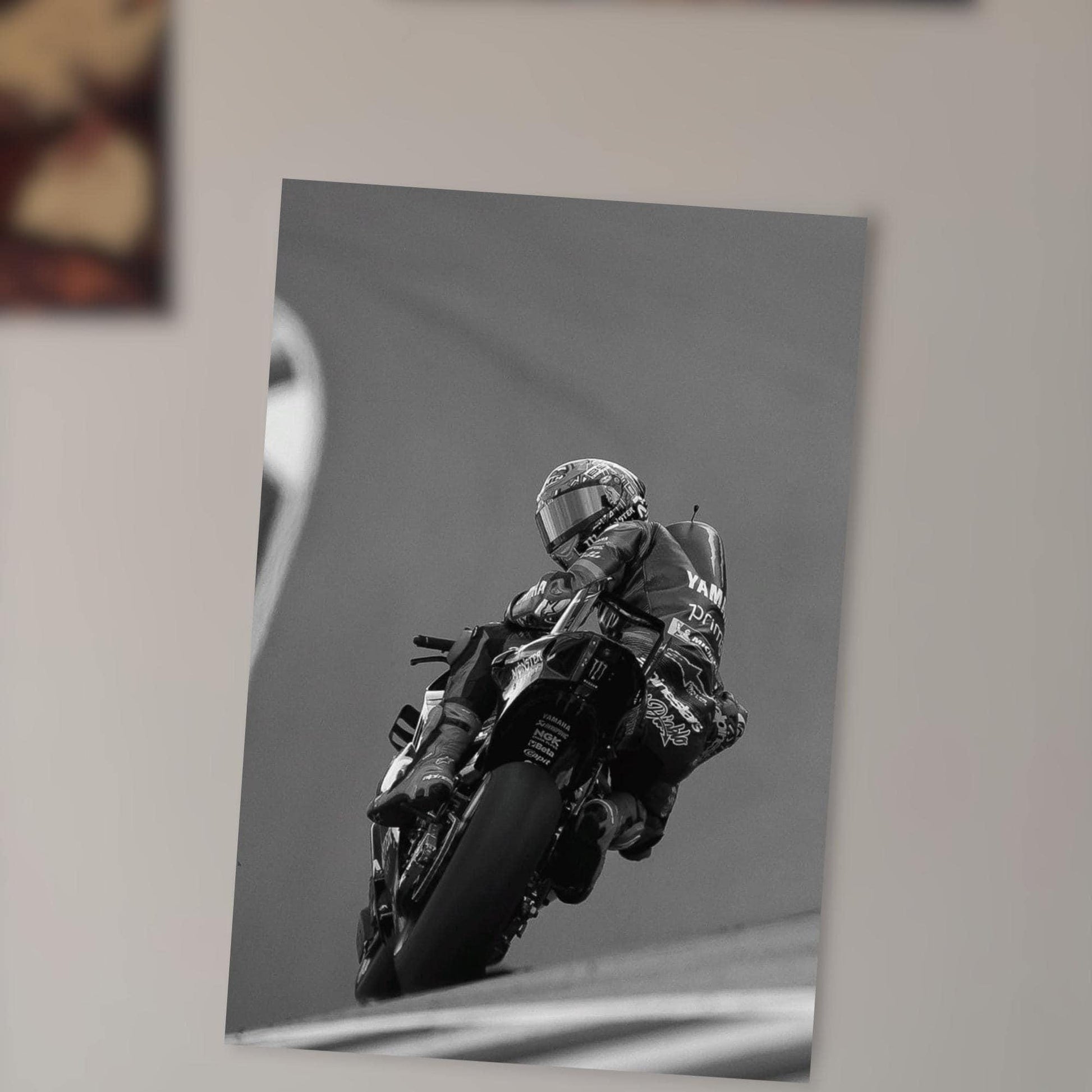 A motorcycle racer in a helmet and protective gear is captured in a dynamic pose, leaning into a turn on a race track.