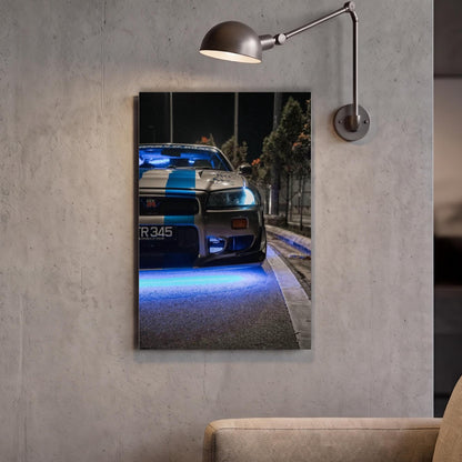 A framed photograph of a police car with blue lights on the front, mounted on a wall next to a lamp.